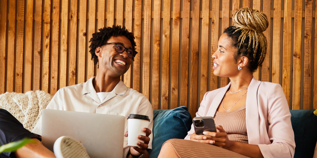 Man and woman in casual business attire sitting in a cafe with a laptop and smartphone